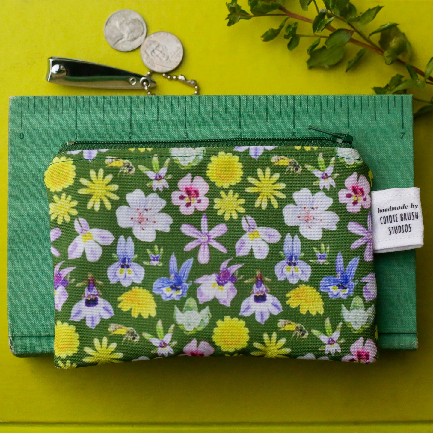 Floral pouch on top of a book with a ruler printed on it showing the pouch to be just over five and a half inches long.