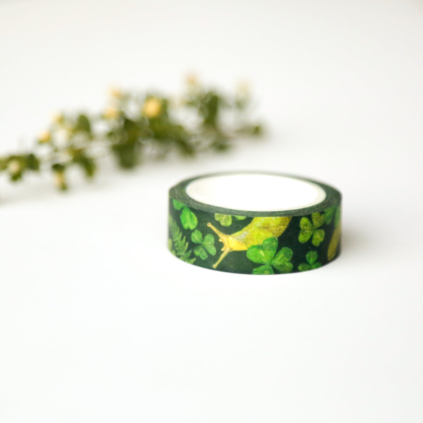 Dark green roll of tape printed with sorrel, ferns, and banana slugs.