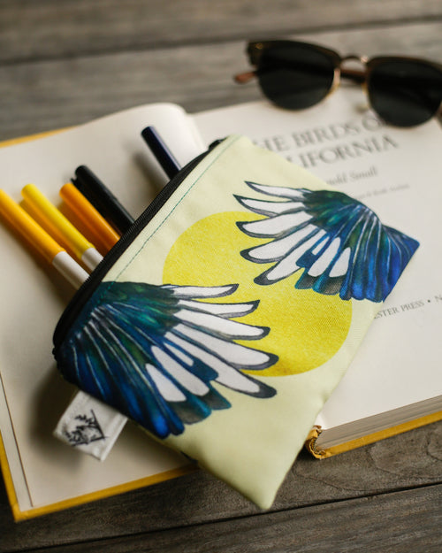 Load image 1 in gallery view. Magpie pouch on top of an open book with markers coming out of the pouch.