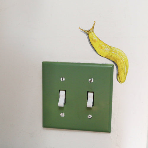 Load image 1 in gallery view. Realistic Banana Slug against white wall looking like it’s climbing around a light switch.