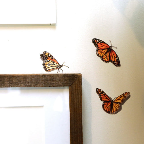 Load image 1 in gallery view. Realistic trio of Monarch Butterflies in various poses around the corner of a picture frame.
