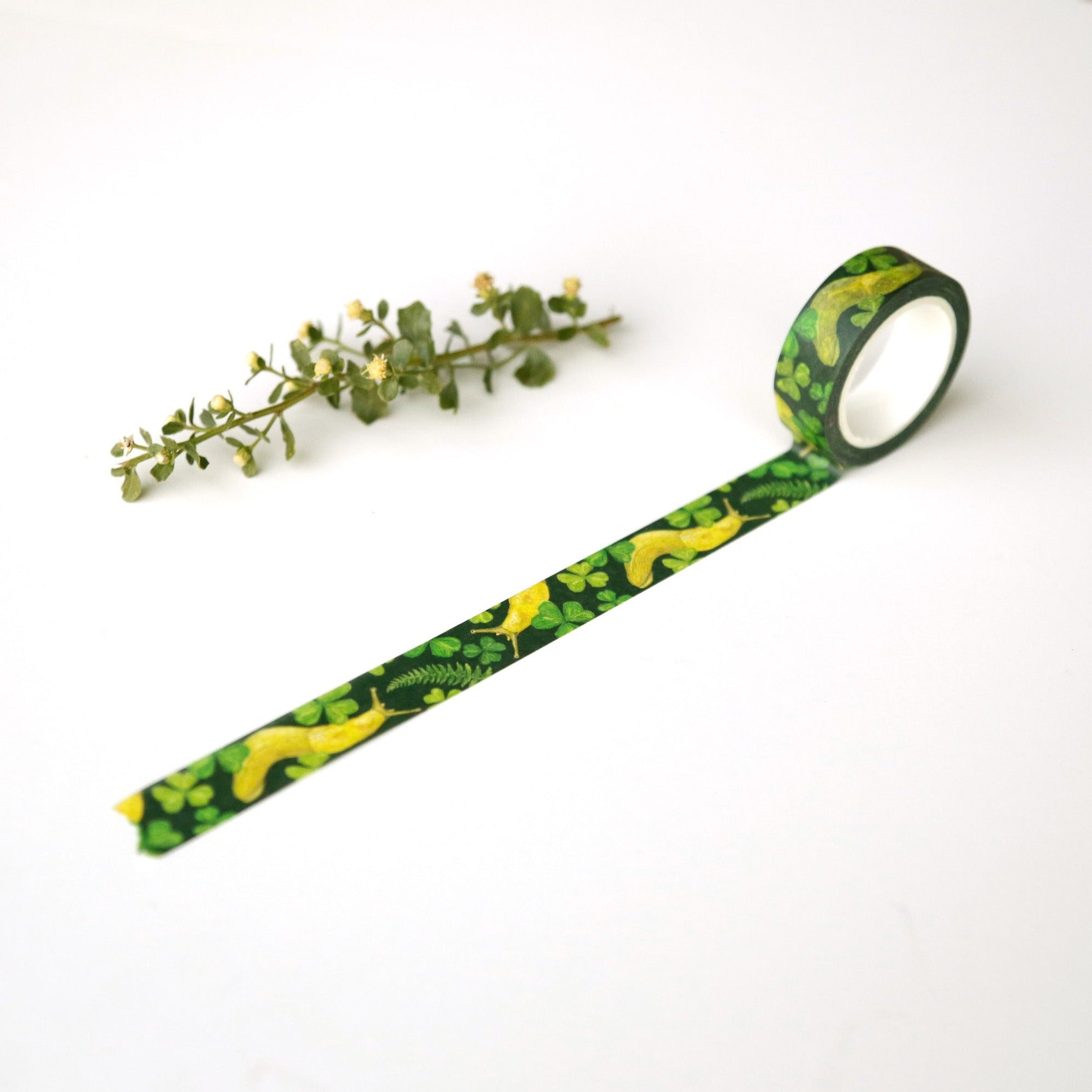 Dark green tape unrolled to show banana slugs, ferns, and sorrel printed on it.